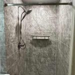 A newly remodeled walk-in shower with elegant gray marble-look tile and a clean, geometric layout. The shower features a modern handheld showerhead, built-in corner shelving, and polished metal fixtures. The crisp lines and luxurious tile pattern create a sleek, spa-like atmosphere—showcasing Bay State Bath’s craftsmanship and attention to detail.