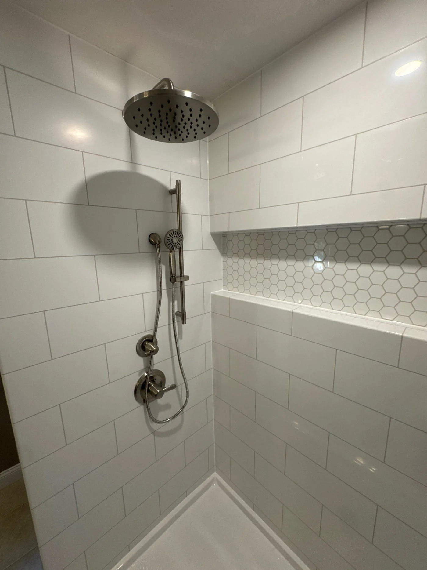 A recessed shower space with a new shower head.