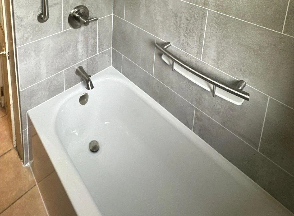 A white bathtub with silver fixtures and gray walls.