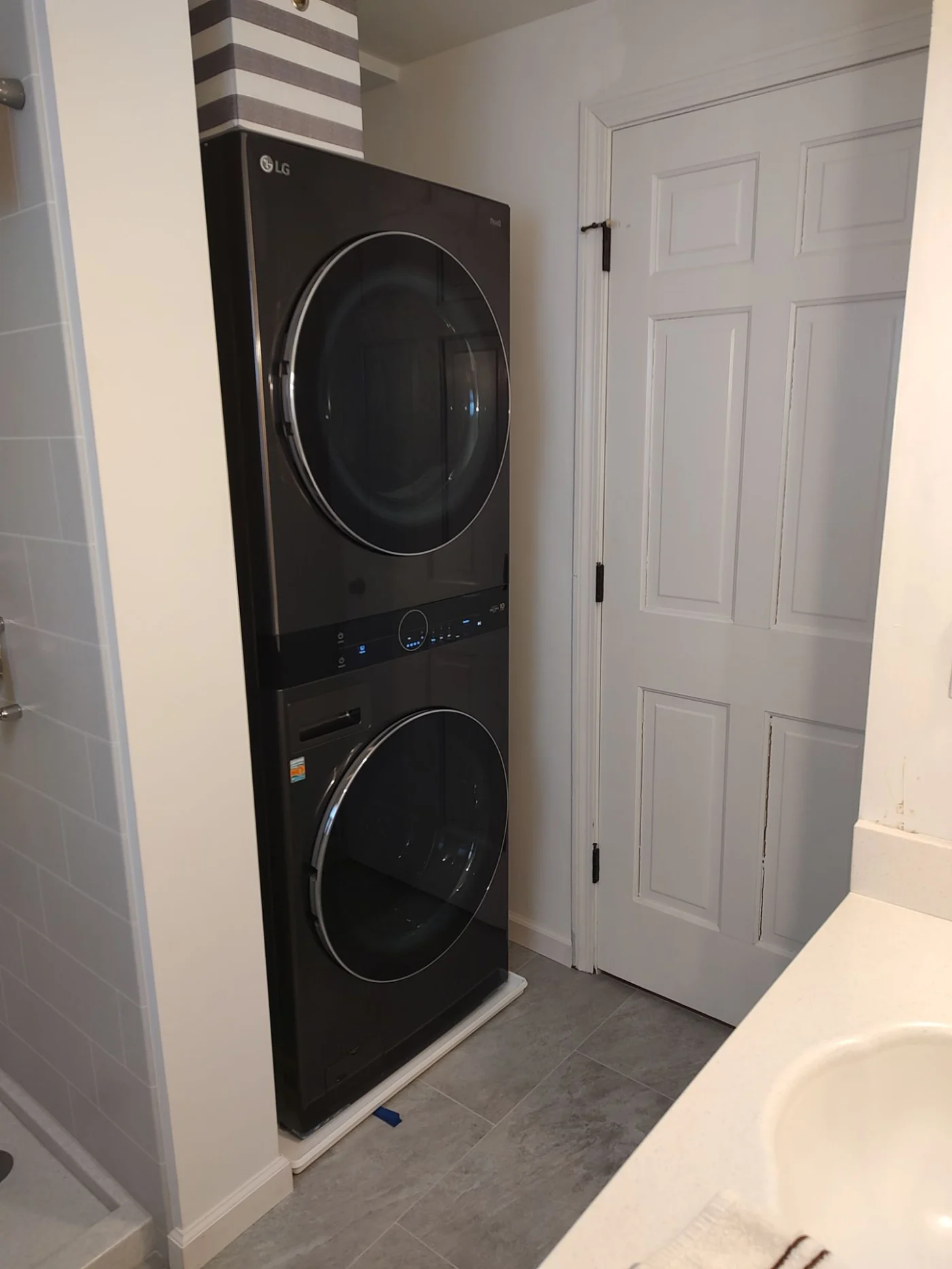 The view from the sink of a washer and dryer in the corner of a bathroom.