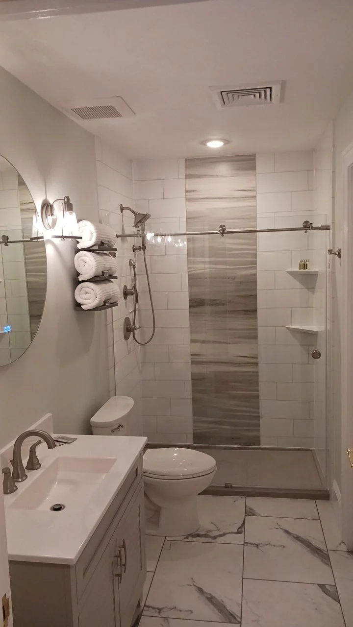 A gray bathroom with a walk-in shower with white and gray walls.