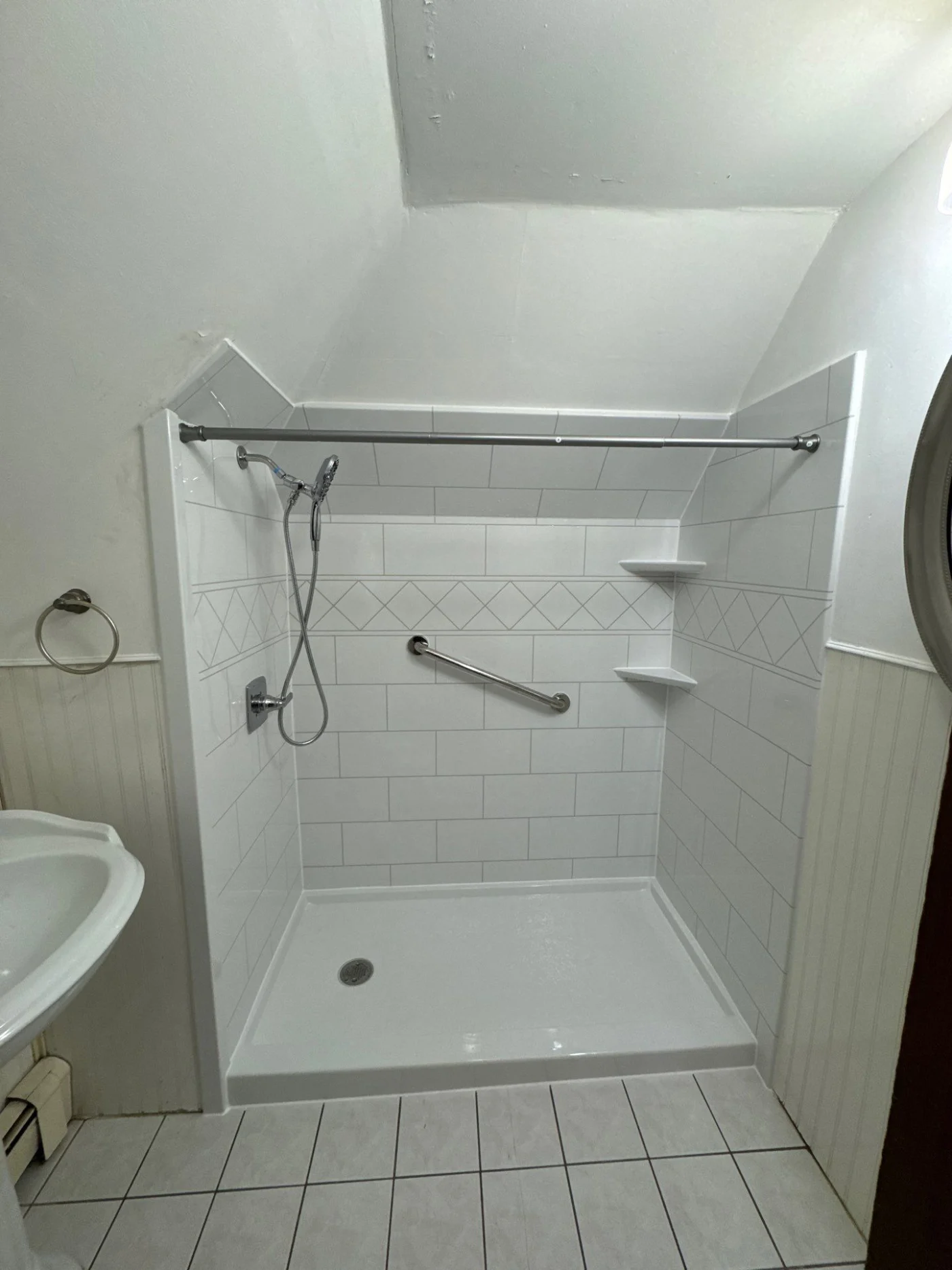 A white-walk-in shower with silver fixtures in a small white bathroom.