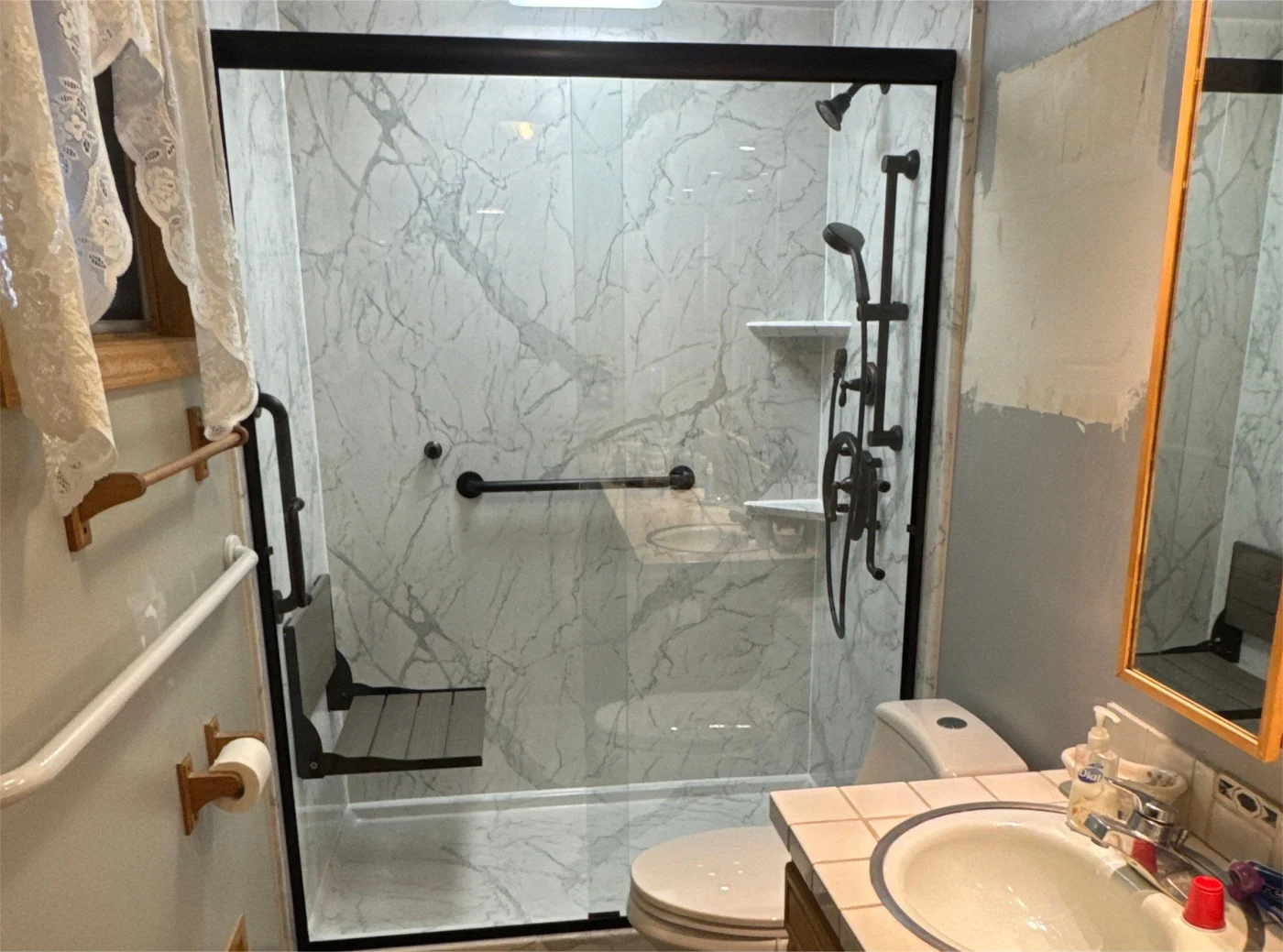 A large walk-in shower with black fixtures, built-in shelves, and a seat.
