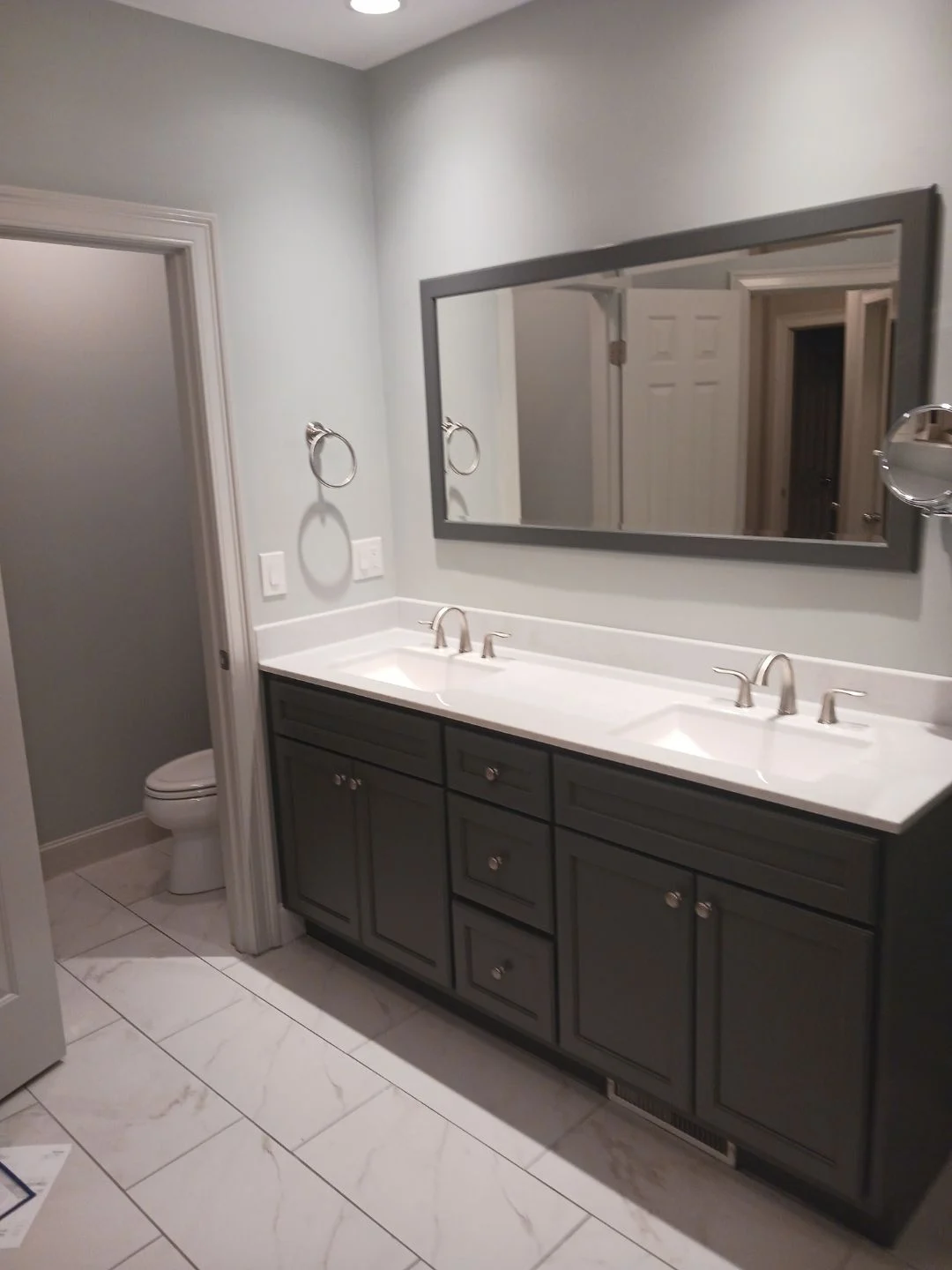 A vanity with several cabinets and two sinks under a long mirror with a gray border.