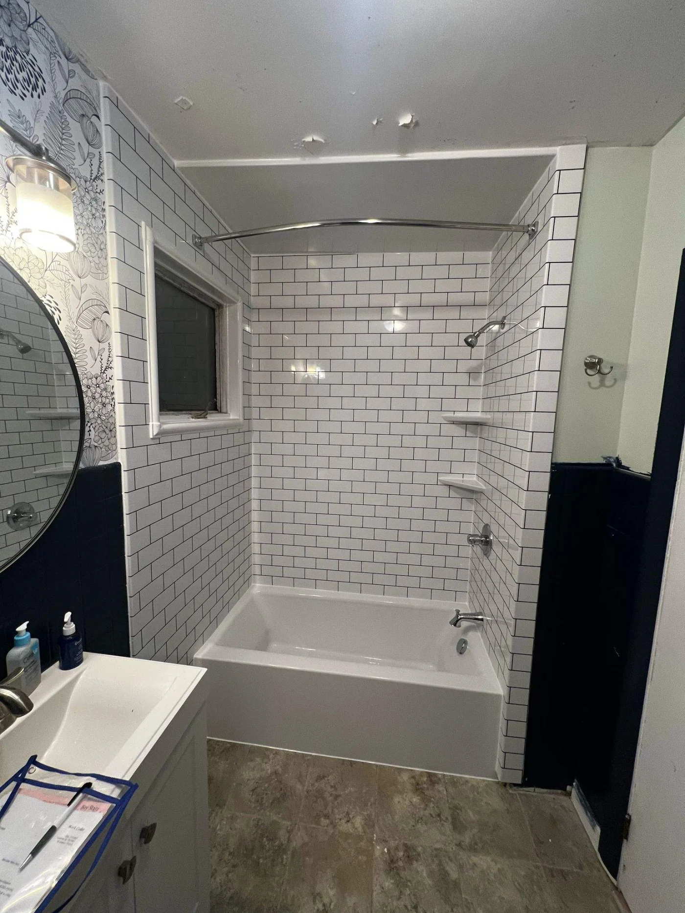 A white bathtub with a subway tile white surround, shelves, and silver fixtures.