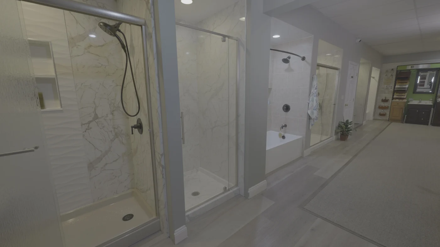 A showroom display features several glass shower enclosures demonstrating different shower base and wall installation options.
